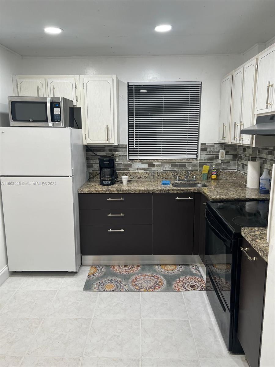 a kitchen with kitchen island granite countertop a sink stove and refrigerator