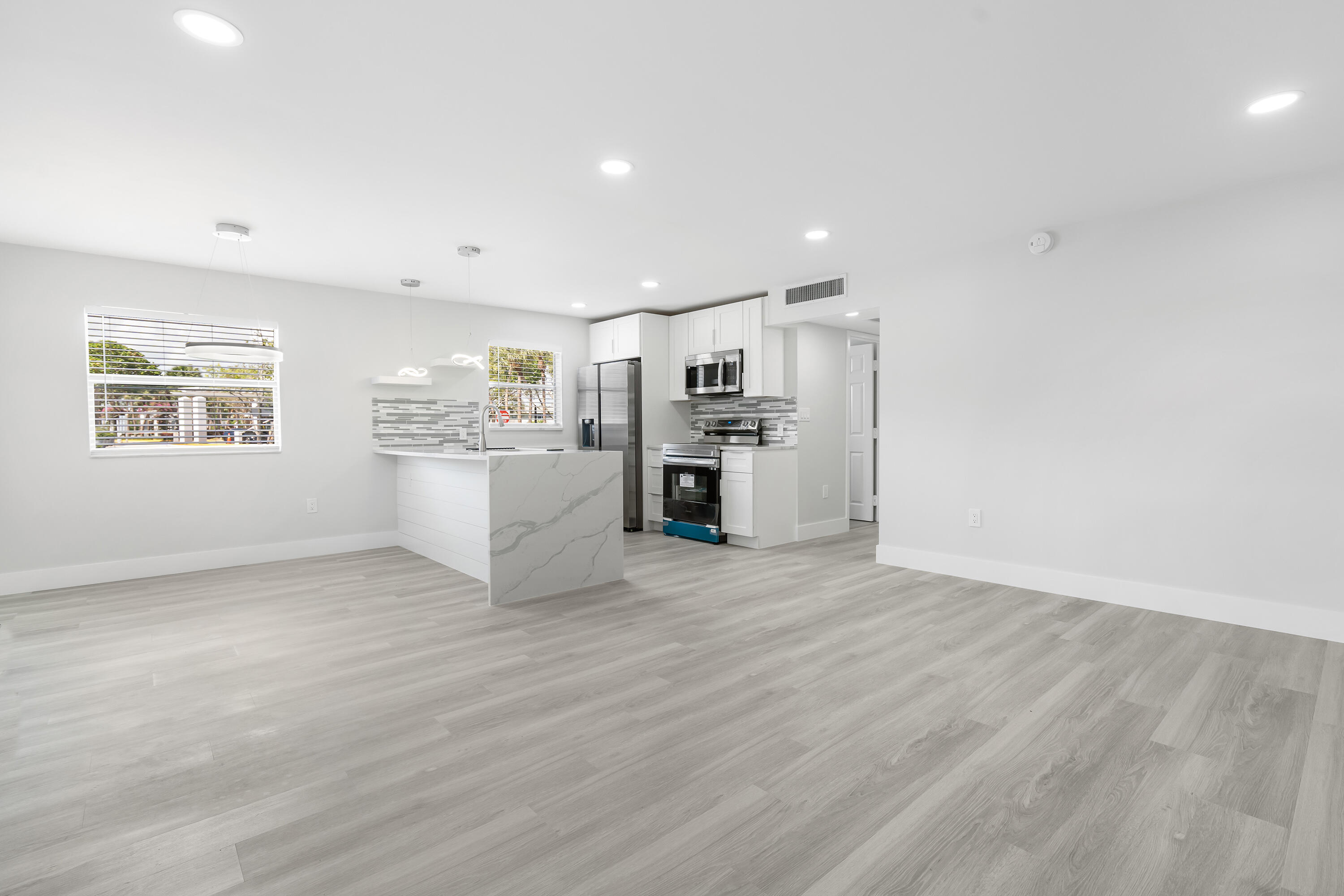 a view of a kitchen with a sink stove cabinets and empty room