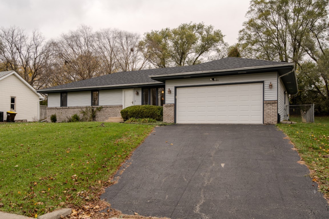 a front view of house with yard and trees in the background