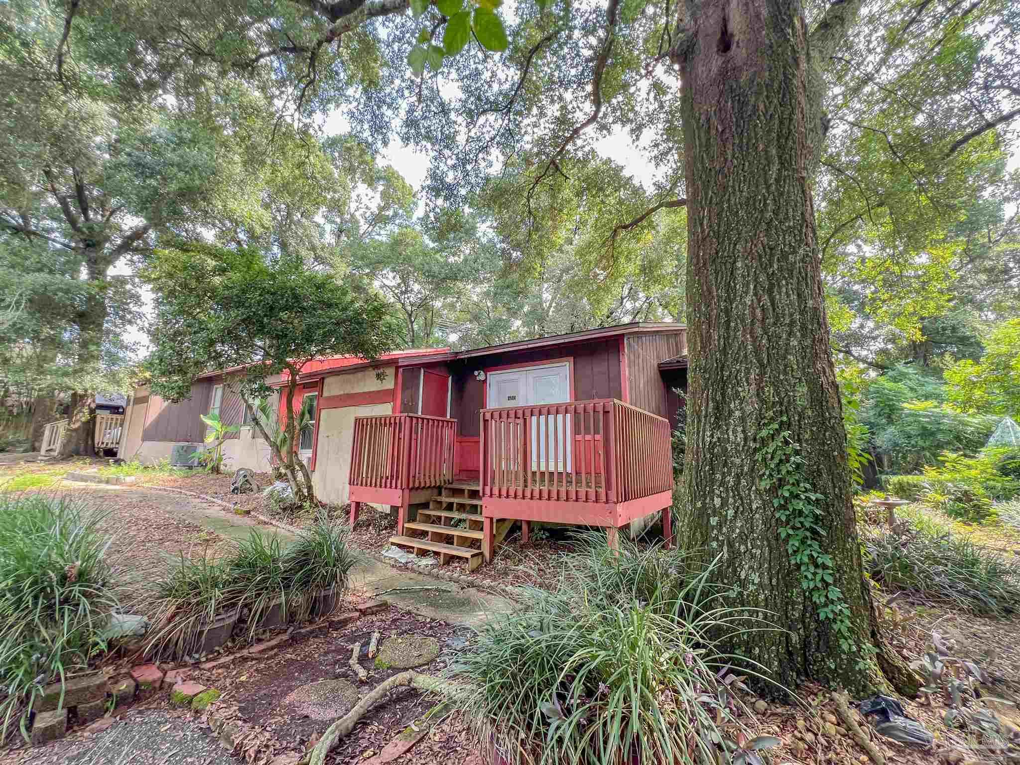 a small yard with large trees and wooden fence