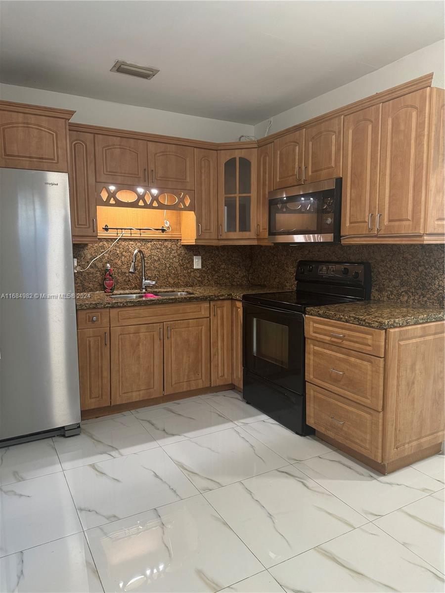 a kitchen with stainless steel appliances granite countertop a stove a sink and a refrigerator