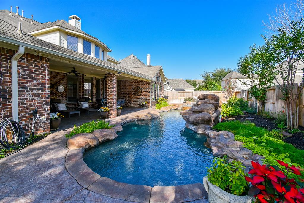 This beautiful backyard is a true outdoor oasis, featuring a pool designed to evoke a natural water feature. The covered patio invites you to sit back and enjoy the tranquil setting, whether you're having meals al fresco or simply soaking in the views of the shimmering water and peaceful surroundings.