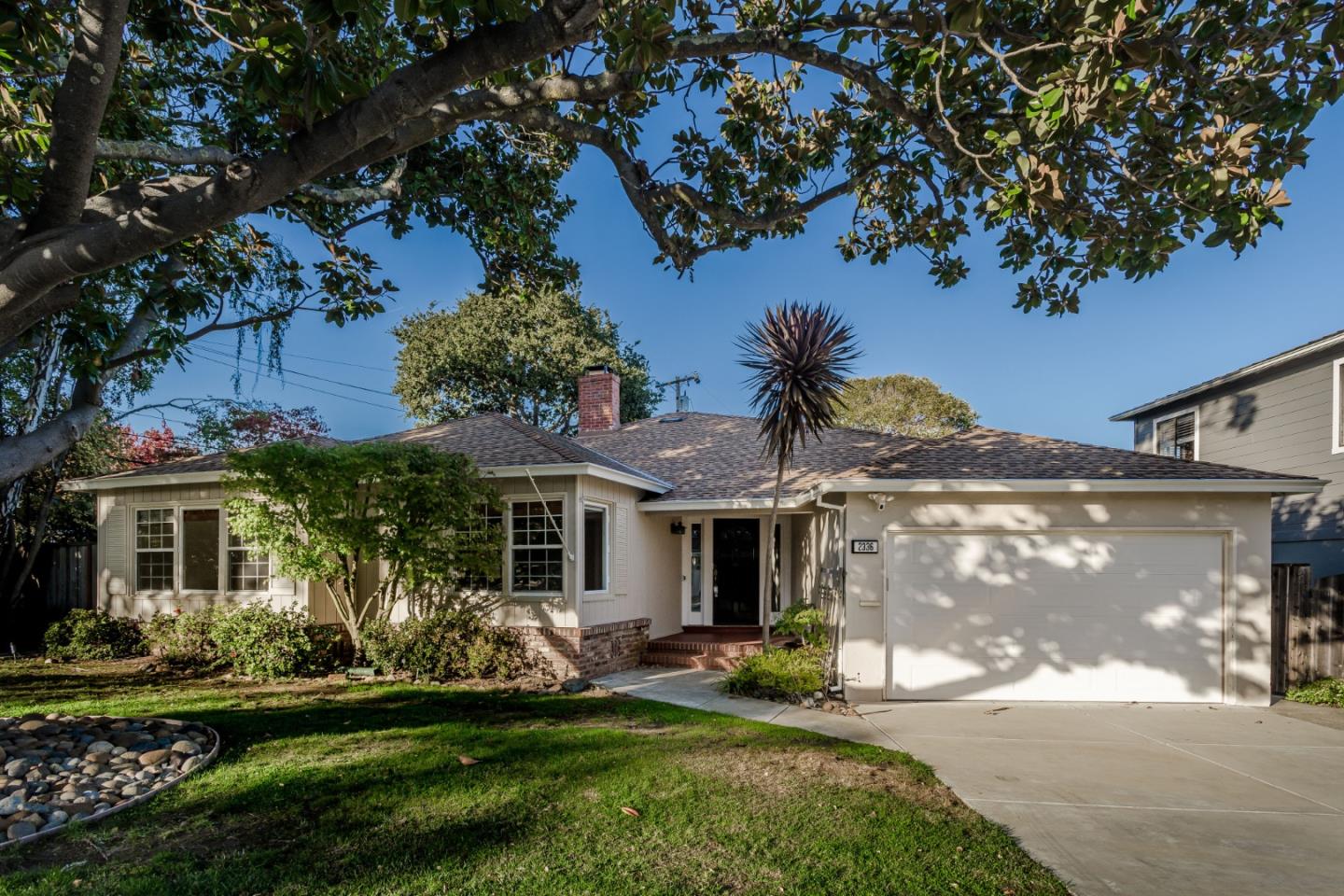 a front view of a house with a garden and tree