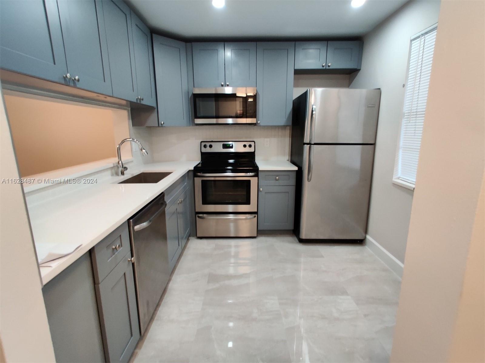 a kitchen with a sink a refrigerator a microwave and cabinets