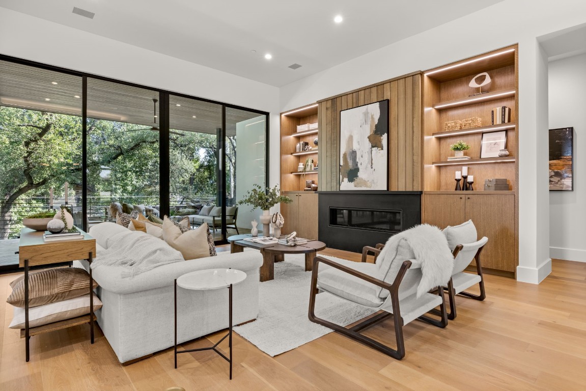 a living room with furniture large window and wooden floor