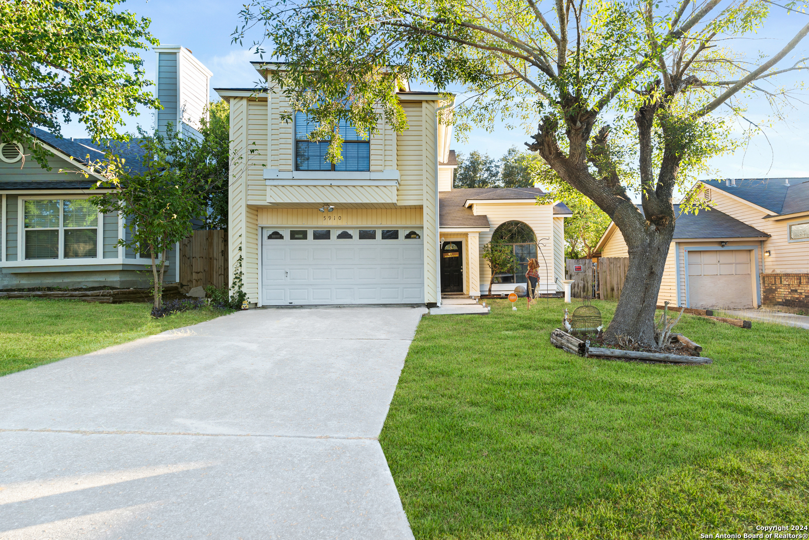 a front view of a house with a garden and trees