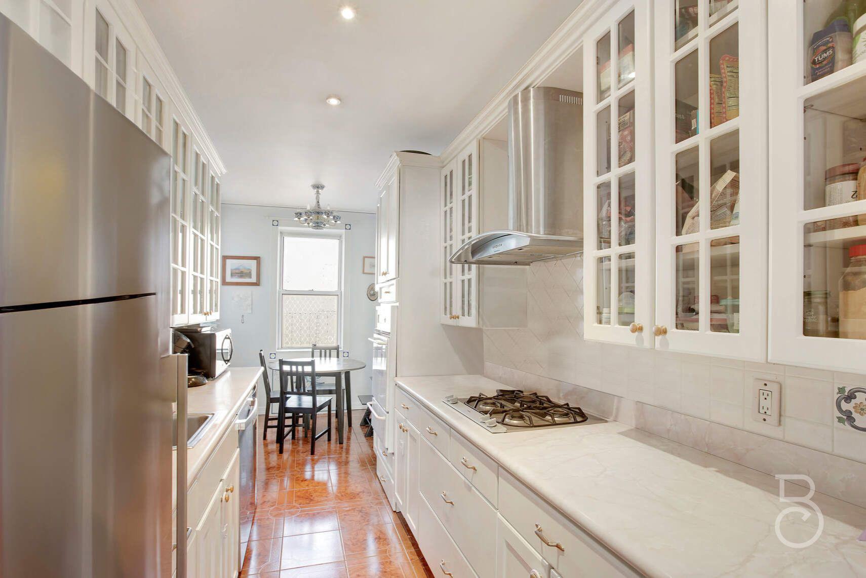 Kitchen featuring light stone countertops, appliances with stainless steel finishes, tasteful backsplash, wall chimney exhaust hood, and white cabinetry