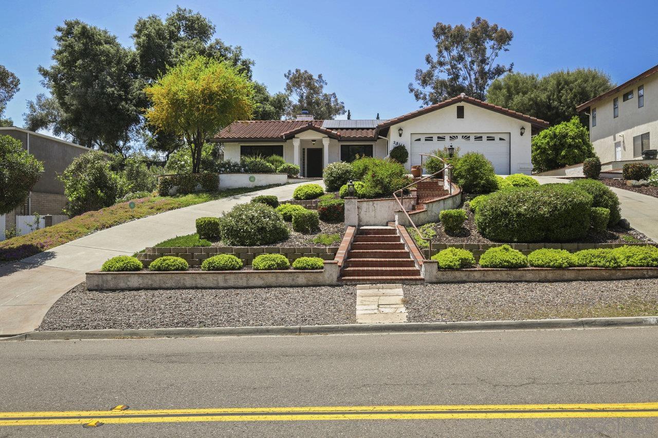 a front view of a house with a yard and potted plants