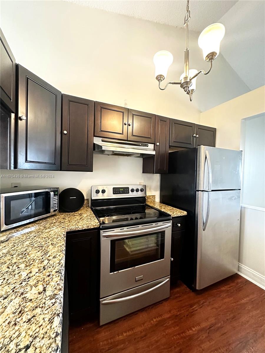 a kitchen with granite countertop a refrigerator oven a sink and dishwasher