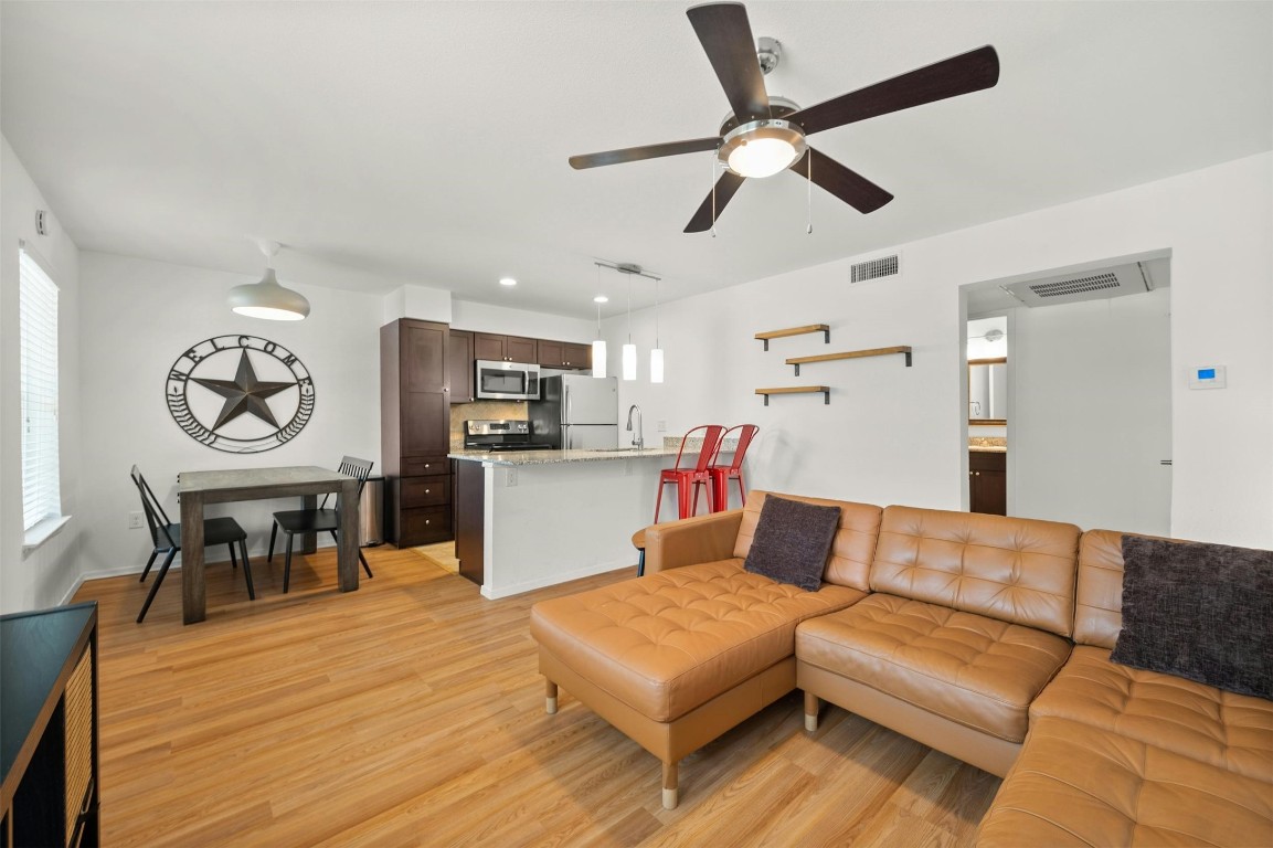 a living room with furniture kitchen view and a wooden floor