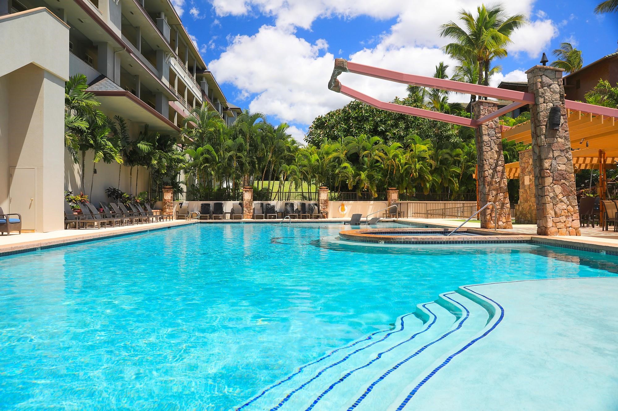 a view of a swimming pool with a bench and trees in the background