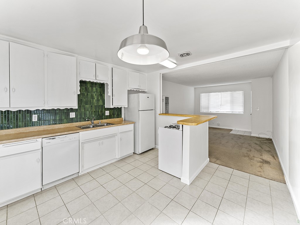 a large white kitchen with a stove a sink dishwasher and a refrigerator