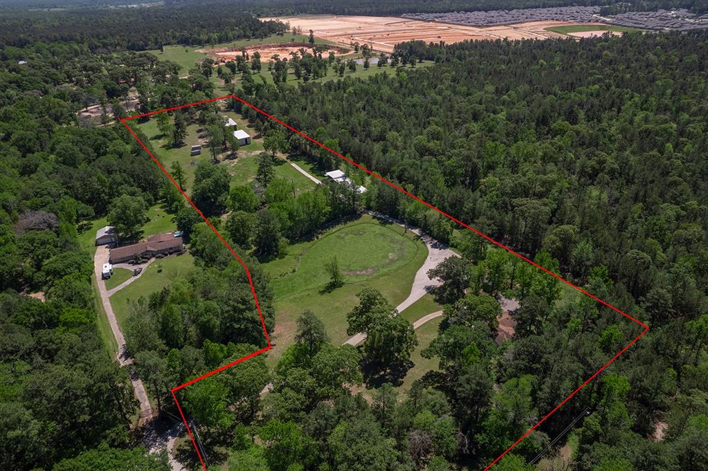 an aerial view of a residential houses with outdoor space and trees