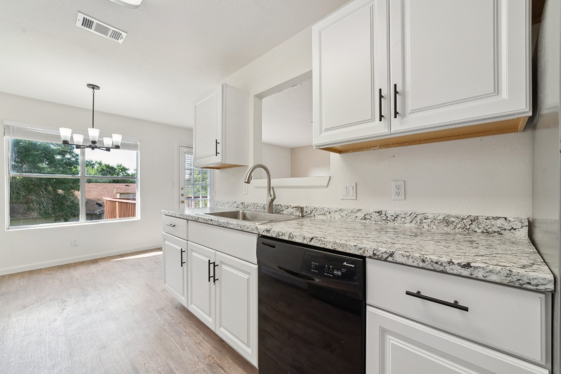 a kitchen with granite countertop white cabinets and a wooden floor