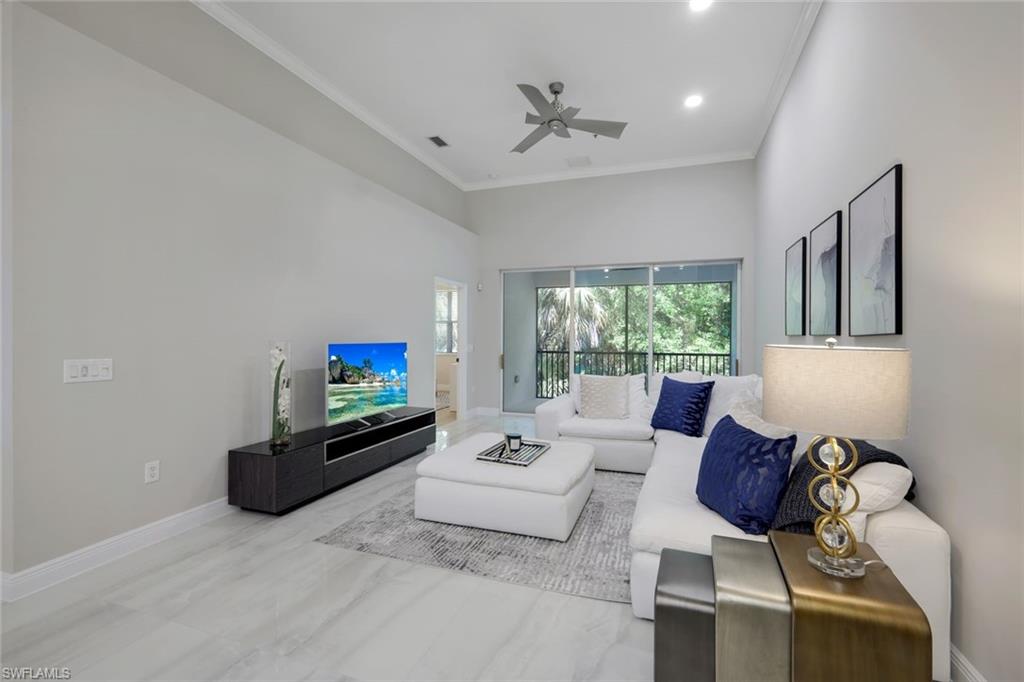 Living room featuring a towering ceiling, ceiling fan, and ornamental molding