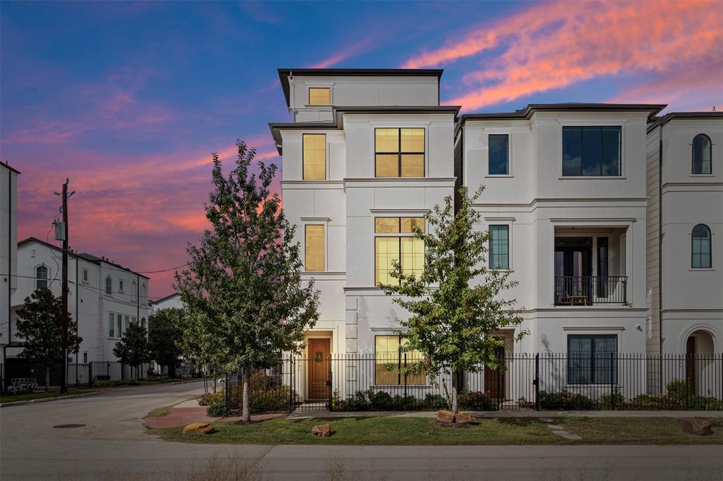 This is a modern multi-story home featuring a clean, light facade, large windows for ample natural light, and a balcony. Nestled in the desirable East End within a gated community.