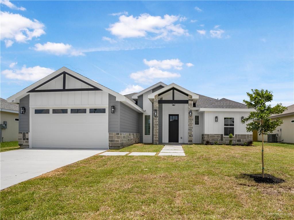 View of front of house featuring a garage, a front yard, and central air condition unit