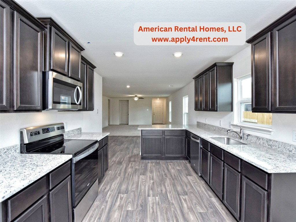 a large kitchen with stainless steel appliances granite countertop a lot of counter space and wooden floor