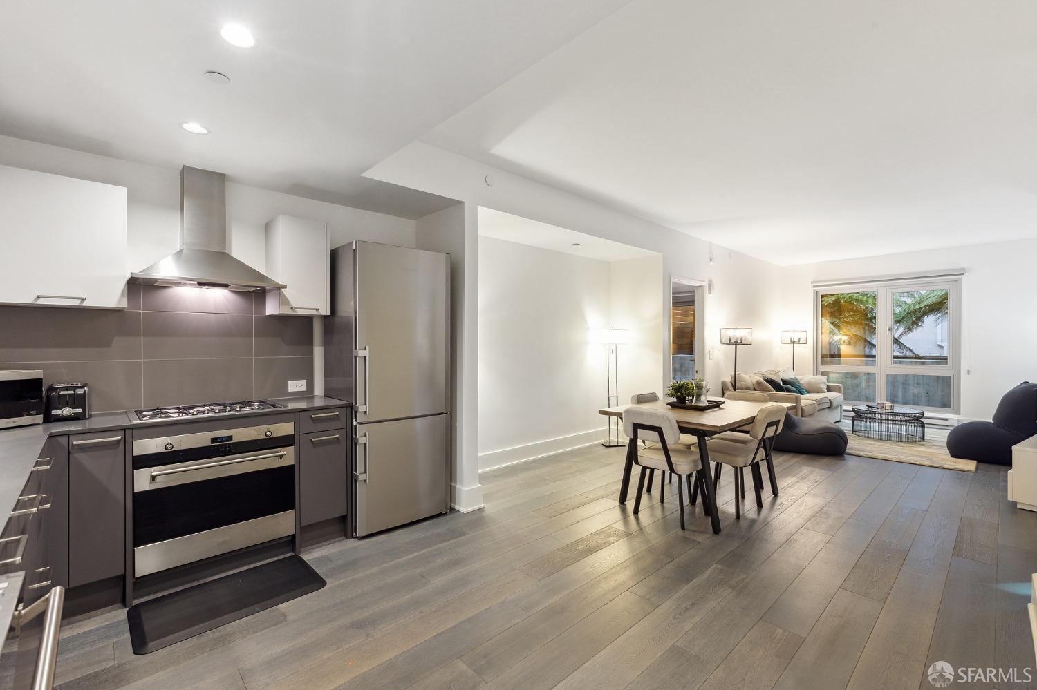 a kitchen with a stove a refrigerator and a dining table with wooden floor