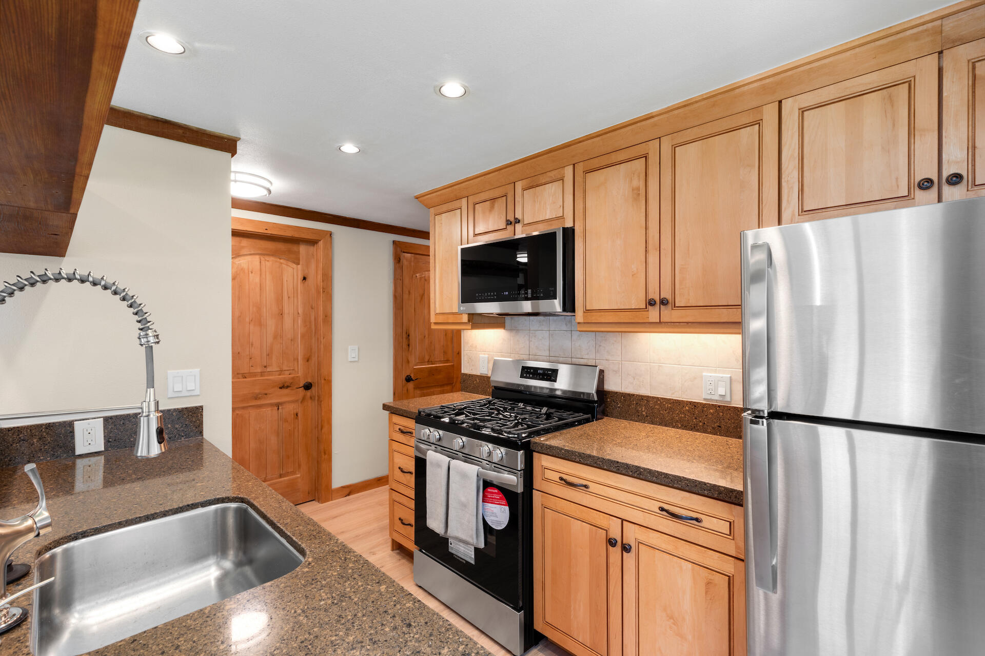 a kitchen with stainless steel appliances granite countertop a refrigerator sink and stove