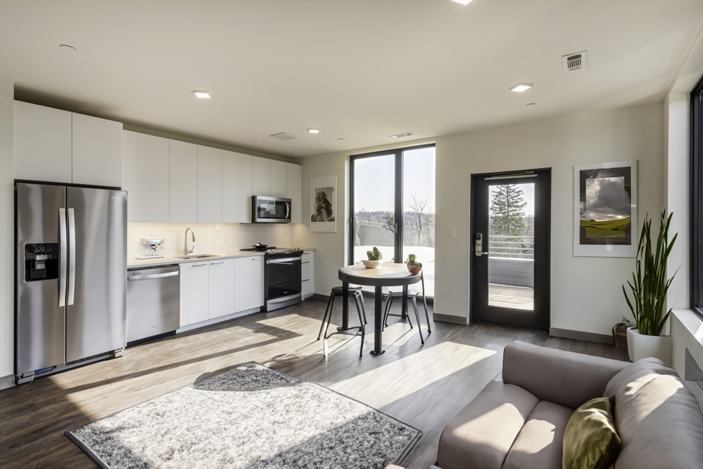 a living room with stainless steel appliances kitchen island granite countertop furniture and a wooden floor