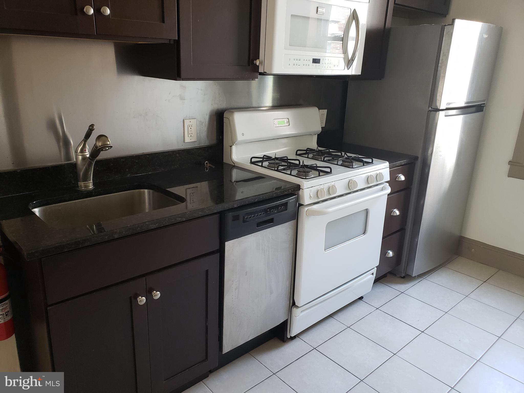 a kitchen with granite countertop a sink stove and refrigerator