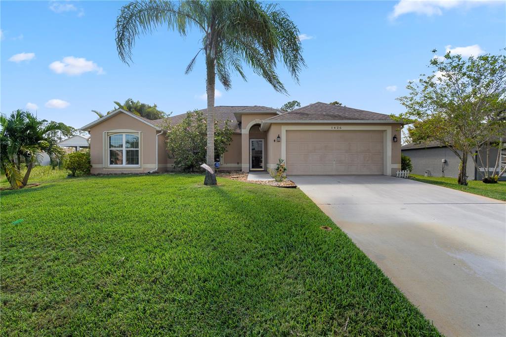 a front view of a house with a garden and palm trees