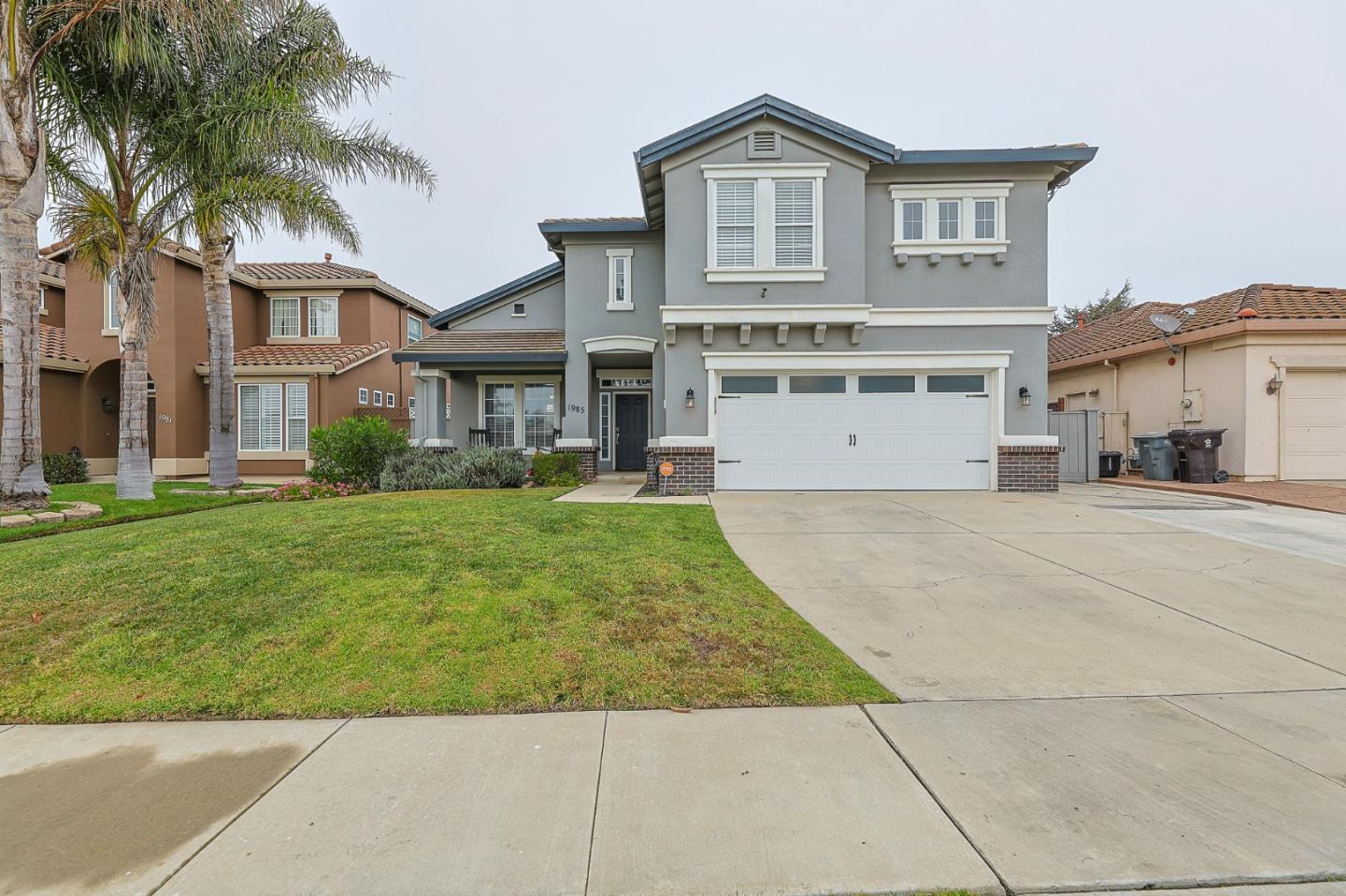 a front view of a house with a yard and palm trees