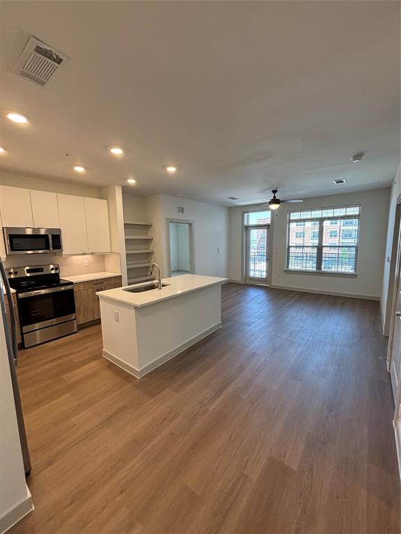 a large kitchen with stainless steel appliances granite countertop a large counter top and a wooden floor