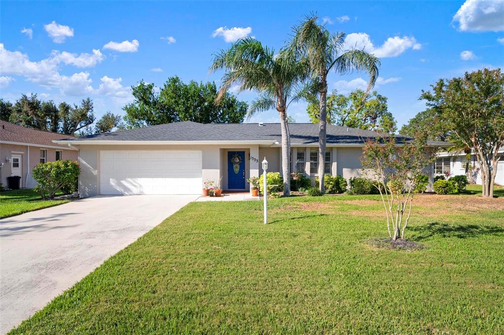 a front view of a house with a yard and palm tree