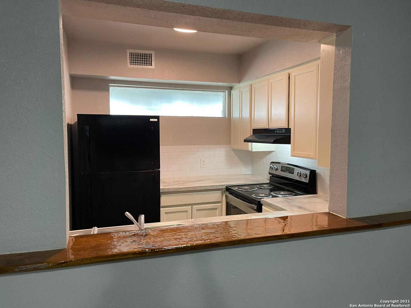 a kitchen with granite countertop white cabinets and refrigerator