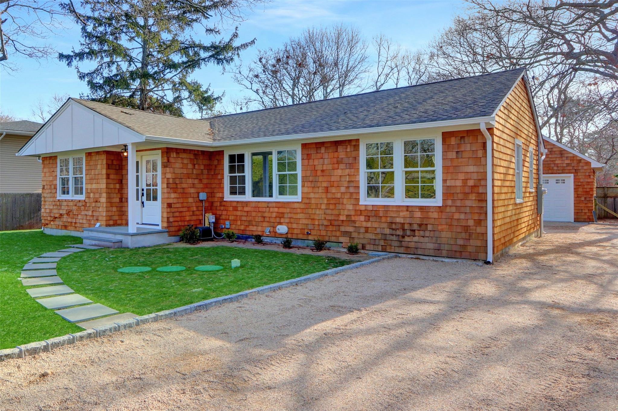 Ranch-style house featuring a garage, an outbuilding, and a front lawn