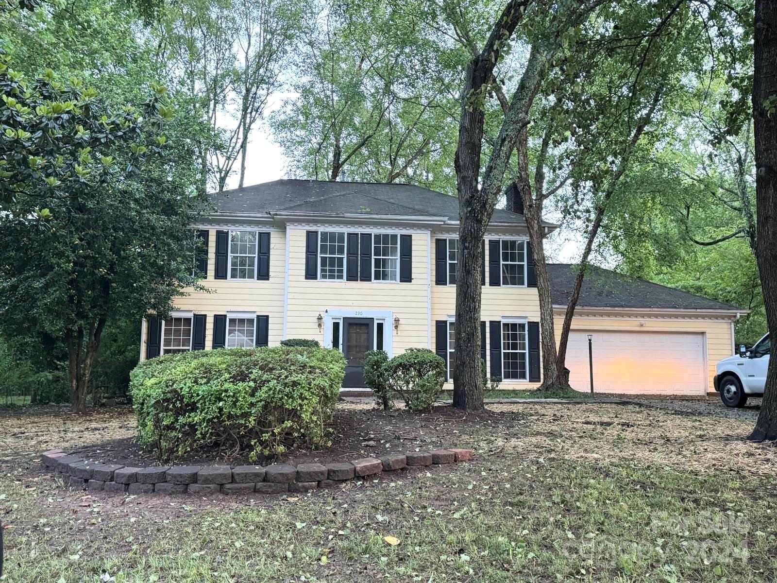 a front view of a house with a yard and trees