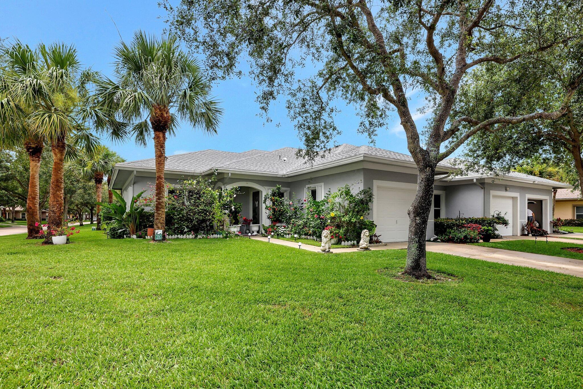 a view of a house with a big yard and palm trees