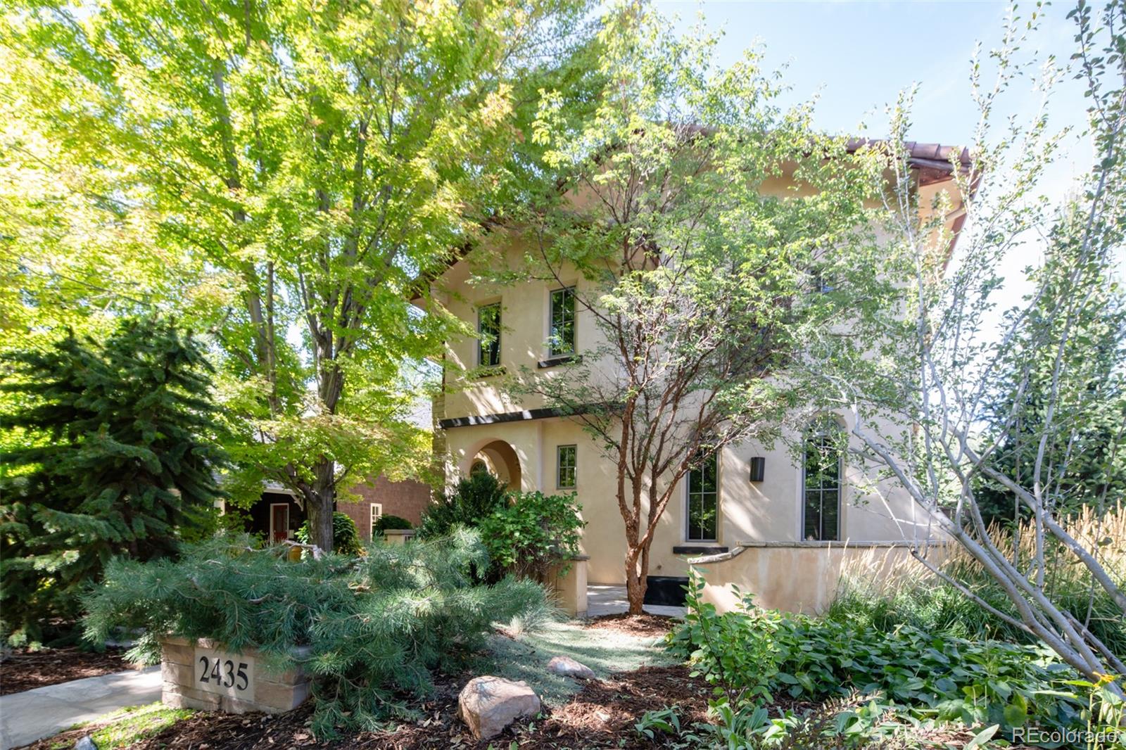 a front view of a house with plants and trees