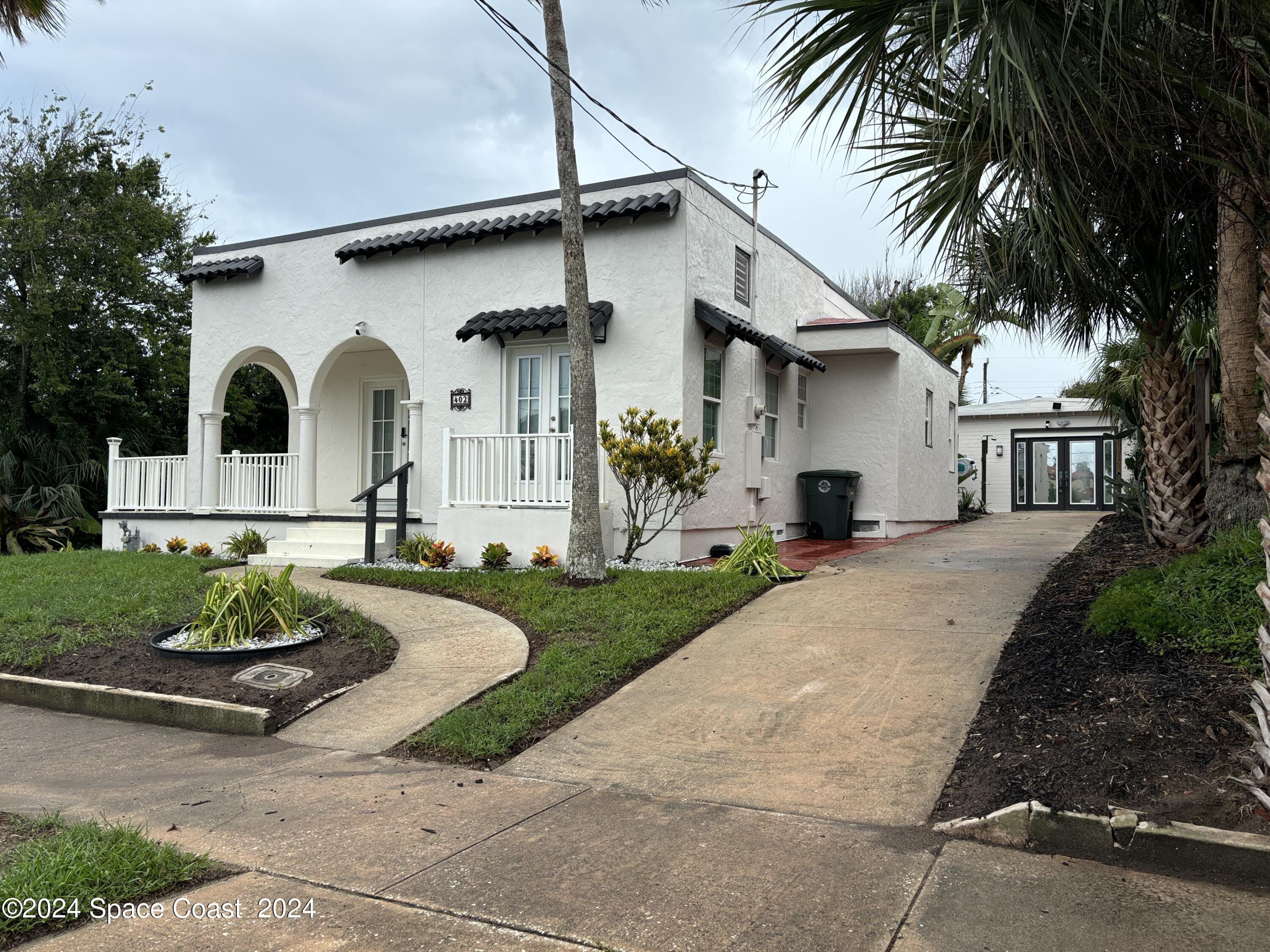 a front view of a house with a garden and plants