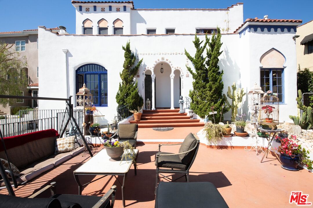 a view of a patio with table and chairs barbeque potted plants and large tree