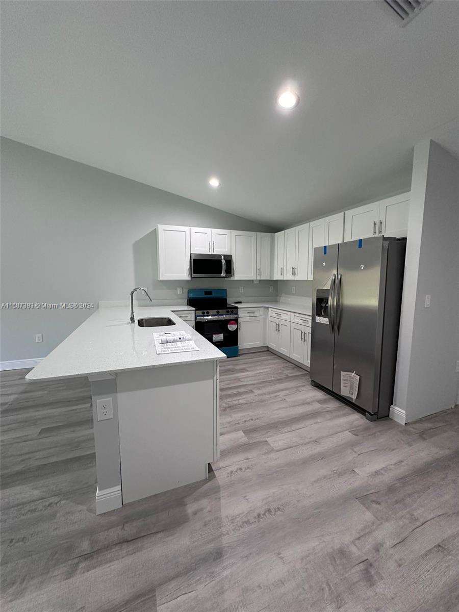 a kitchen with stainless steel appliances a refrigerator sink and microwave