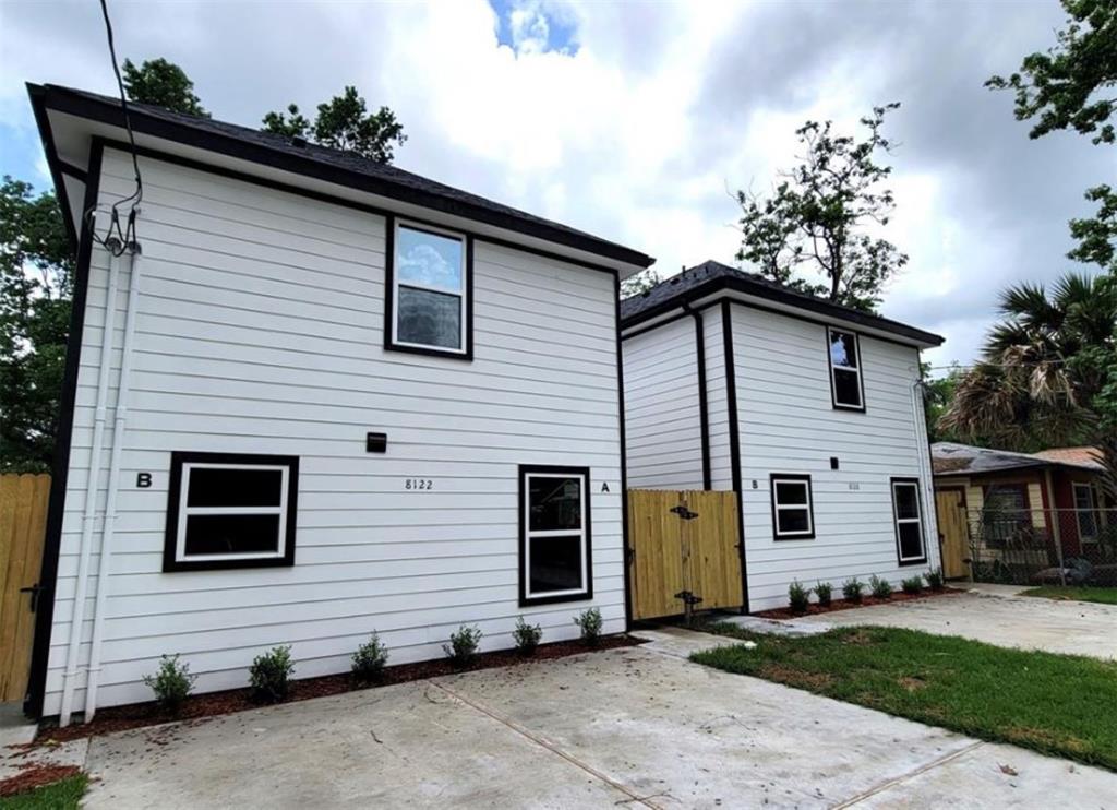 Modern two-story duplex with fresh white siding, contrasting black trim, and a newly poured concrete driveway. Each unit offers private entry and ample natural light.