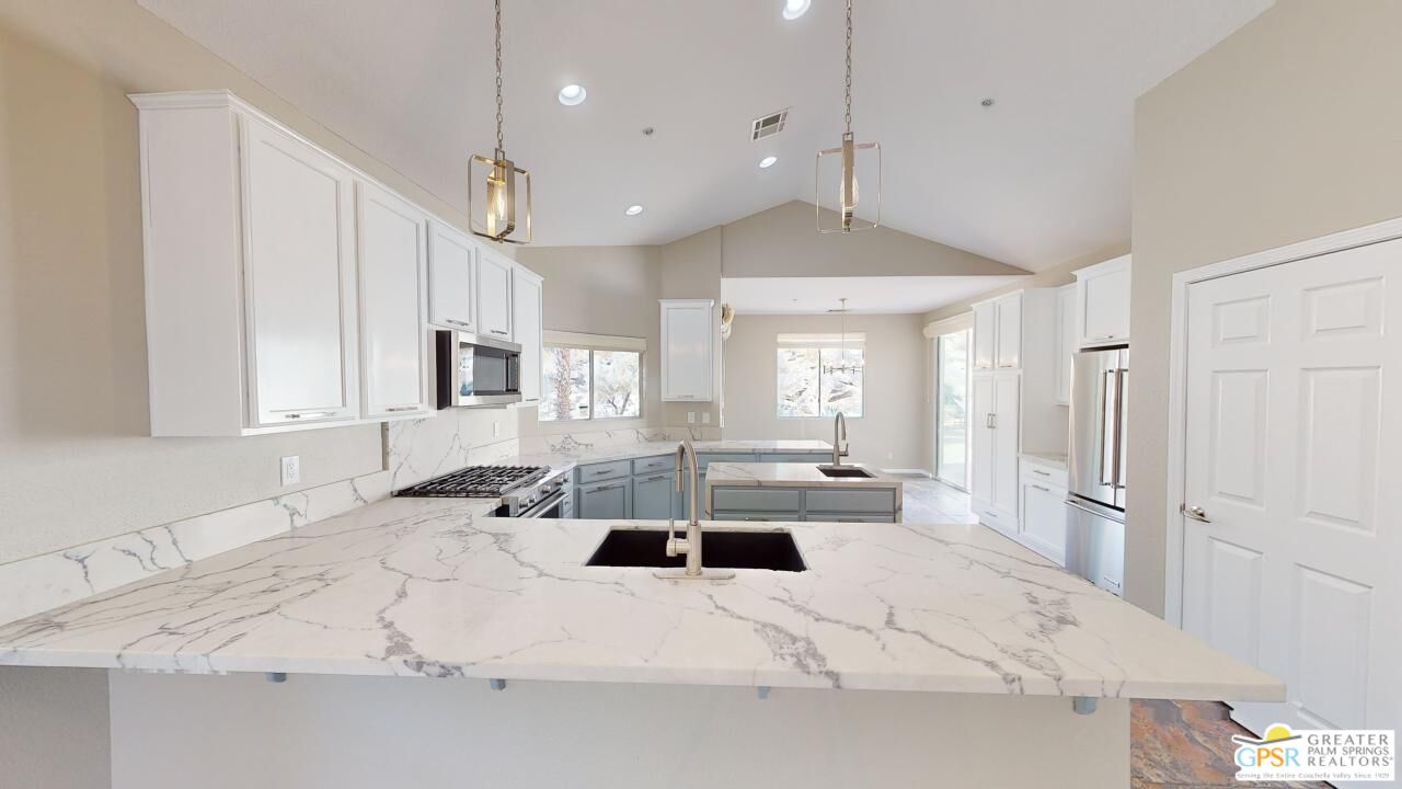 a large white kitchen with a large window a sink and stainless steel appliances