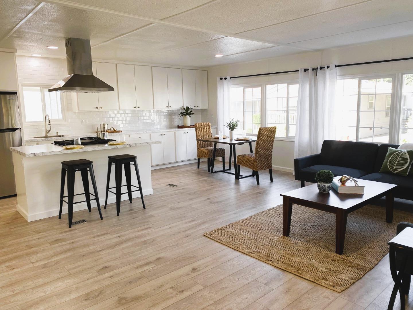 a living room with furniture a wooden floor and a view of kitchen