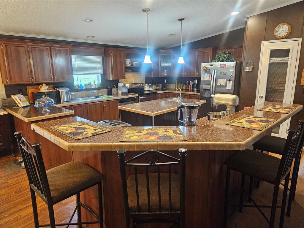 a kitchen with a stove a refrigerator a sink a dining table and chairs with wooden floor