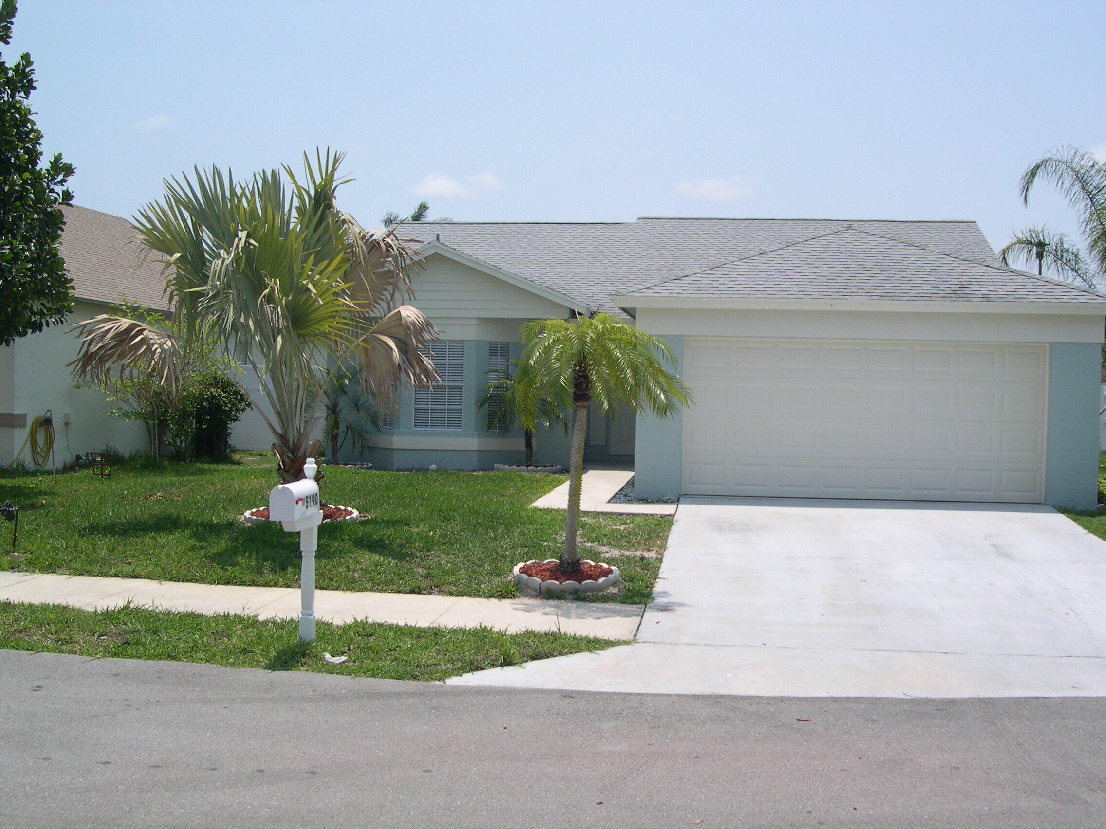 a palm tree sitting in front of a house with a yard