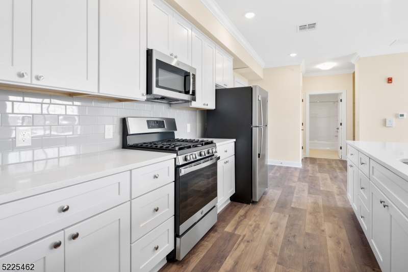 a kitchen with stainless steel appliances a refrigerator stove and white cabinets