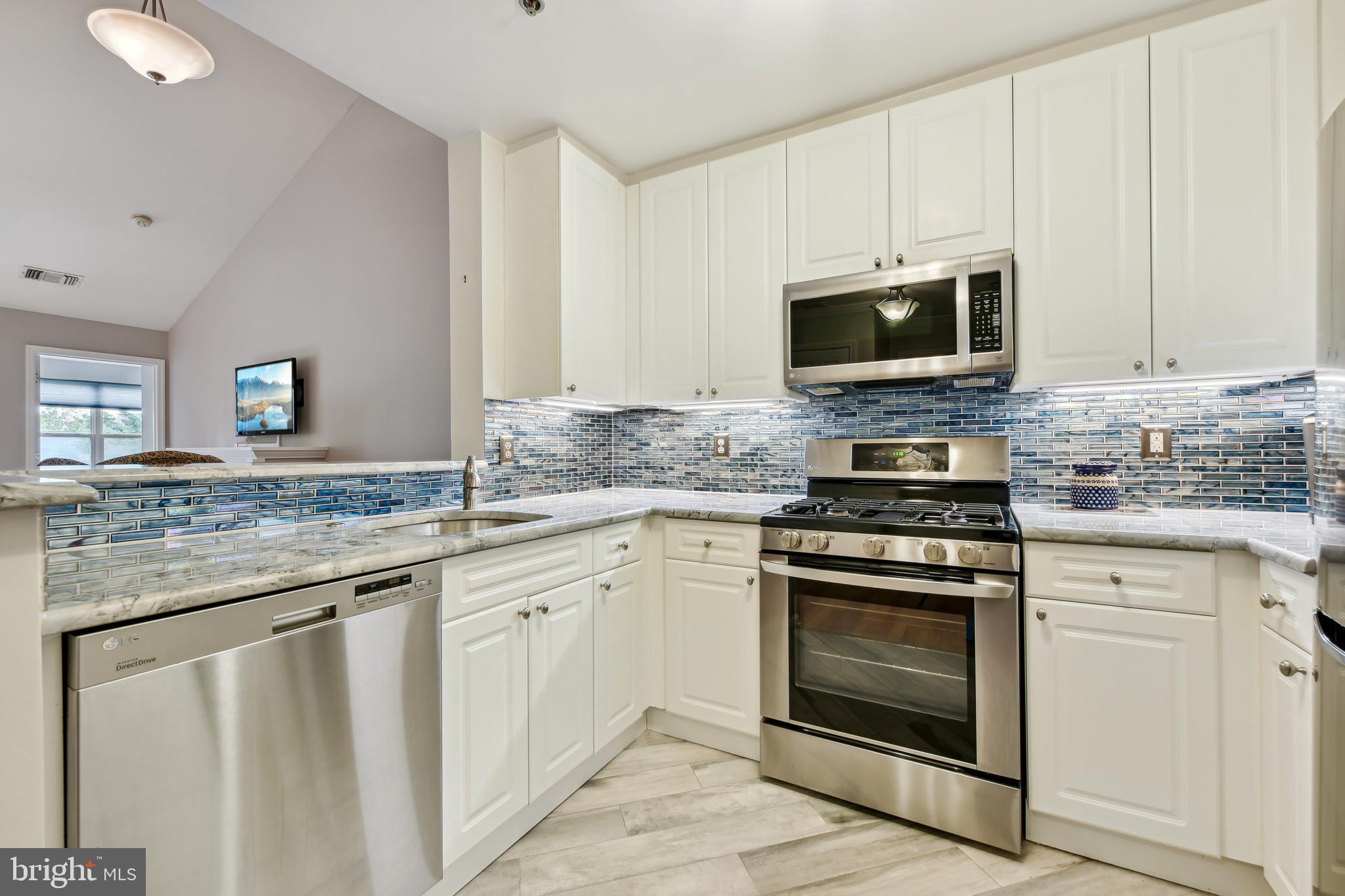 a kitchen with granite countertop white cabinets and stainless steel appliances