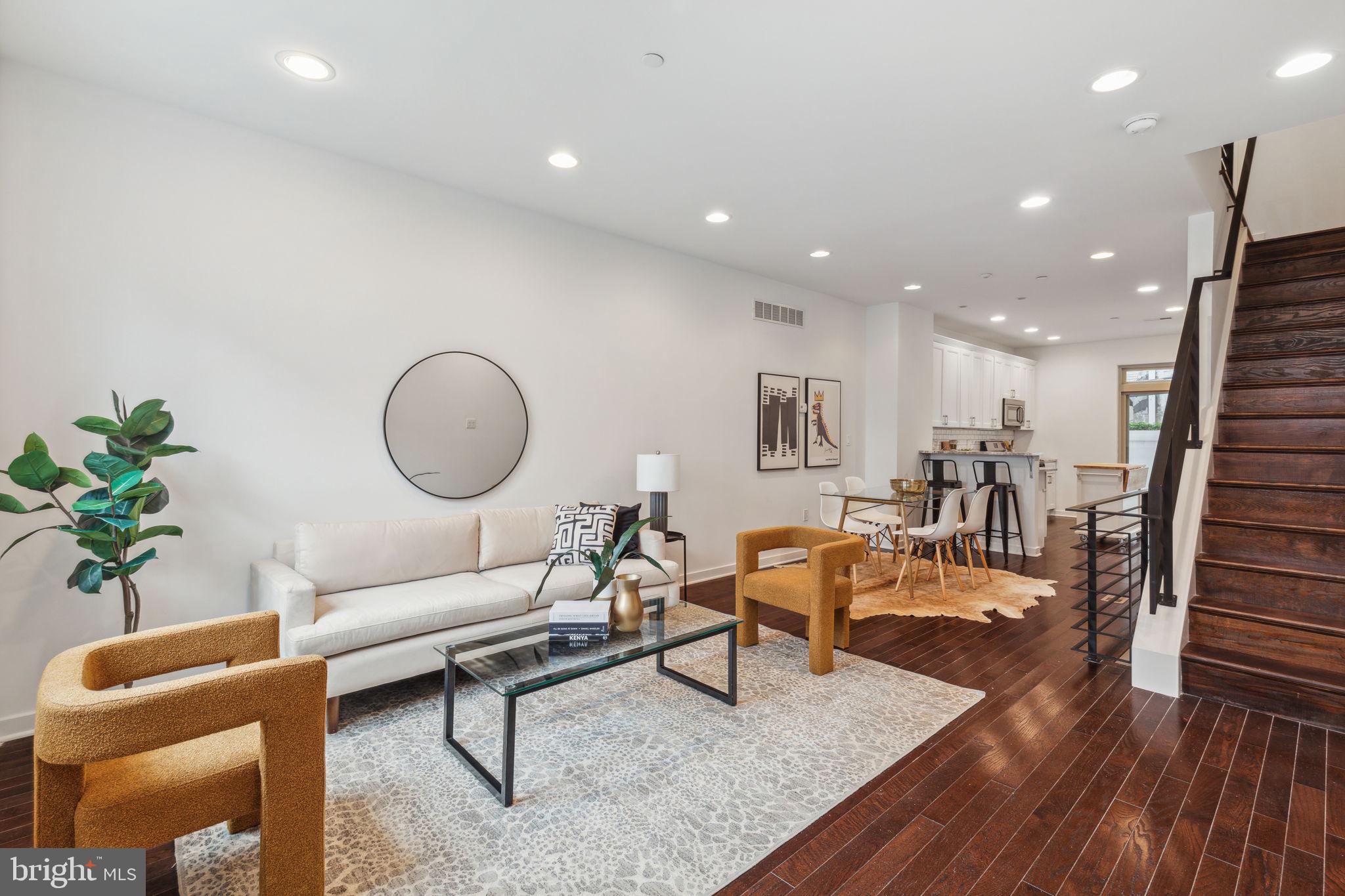 a living room with furniture kitchen view and a wooden floor