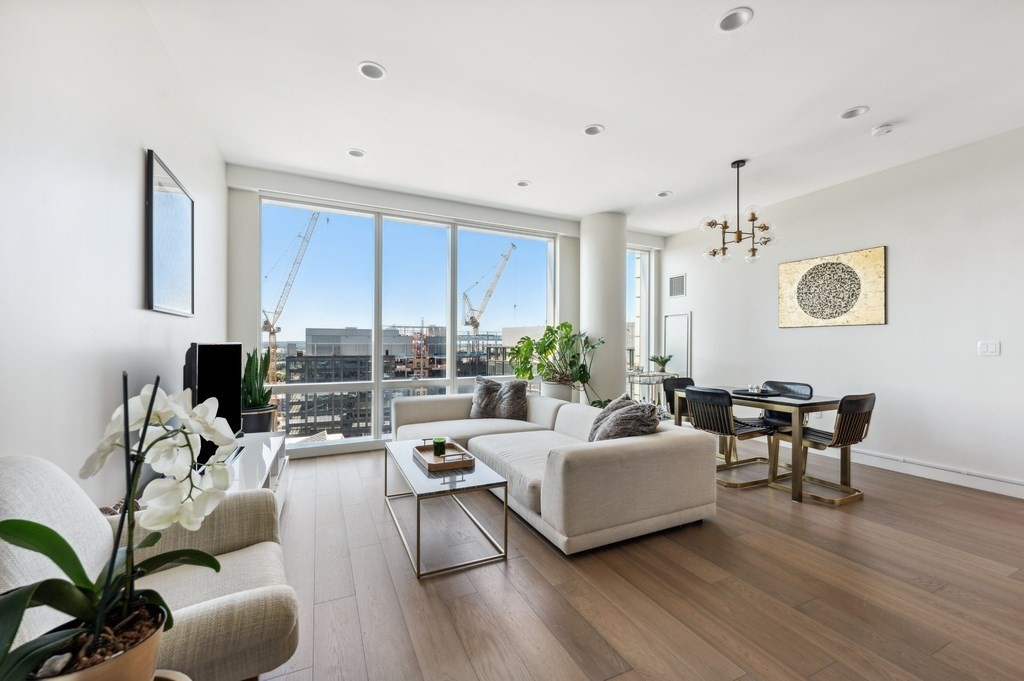 a living room with furniture kitchen view and a wooden floor