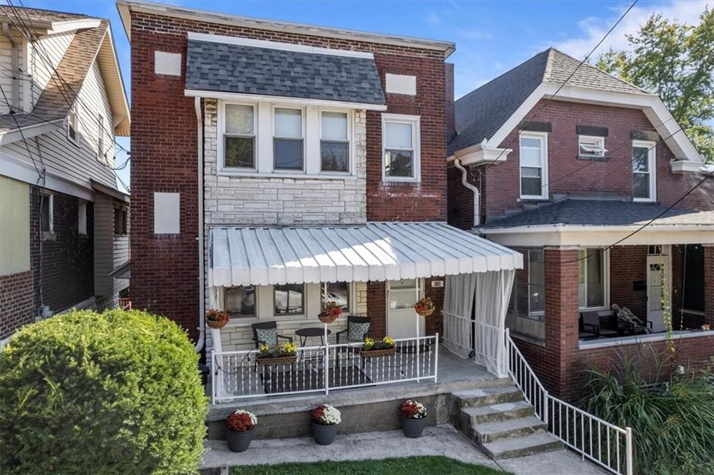 a view of a brick house with a patio and a yard