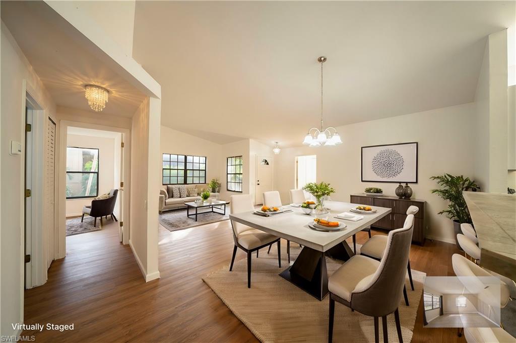 Dining space with dark wood-type flooring, lofted ceiling, and a notable chandelier