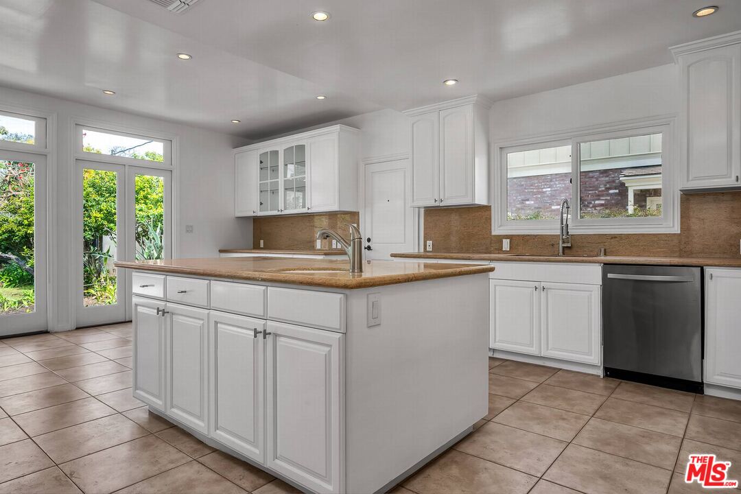 a kitchen with kitchen island granite countertop a sink cabinets and stainless steel appliances